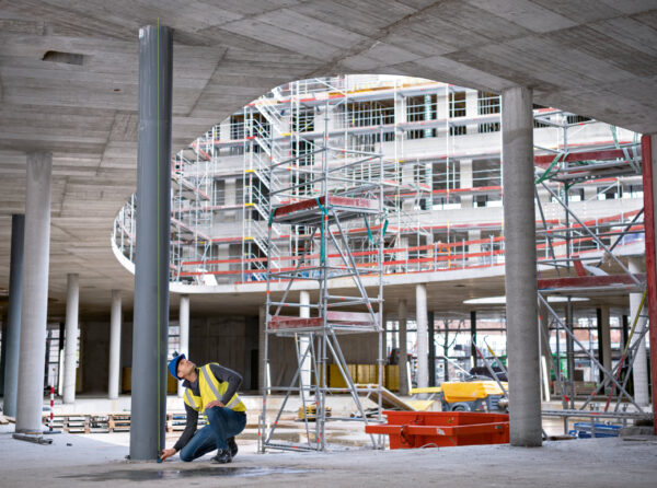 Measuring vertical distance with a high-visibility green beam laser on a large scale construction project.